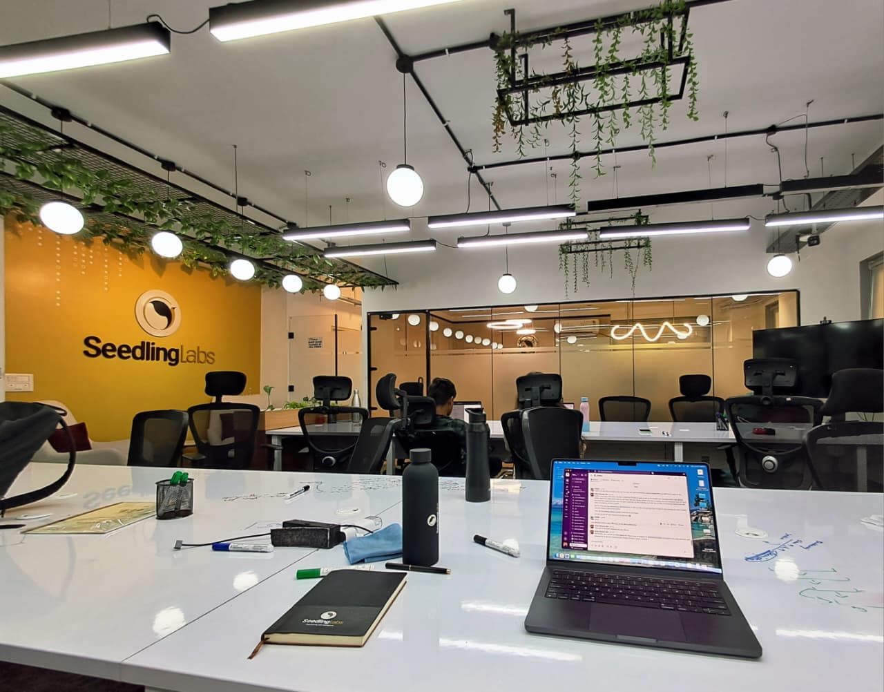 The SeedlingLabs office floor in Bengaluru, desks and a laptop open to Slack